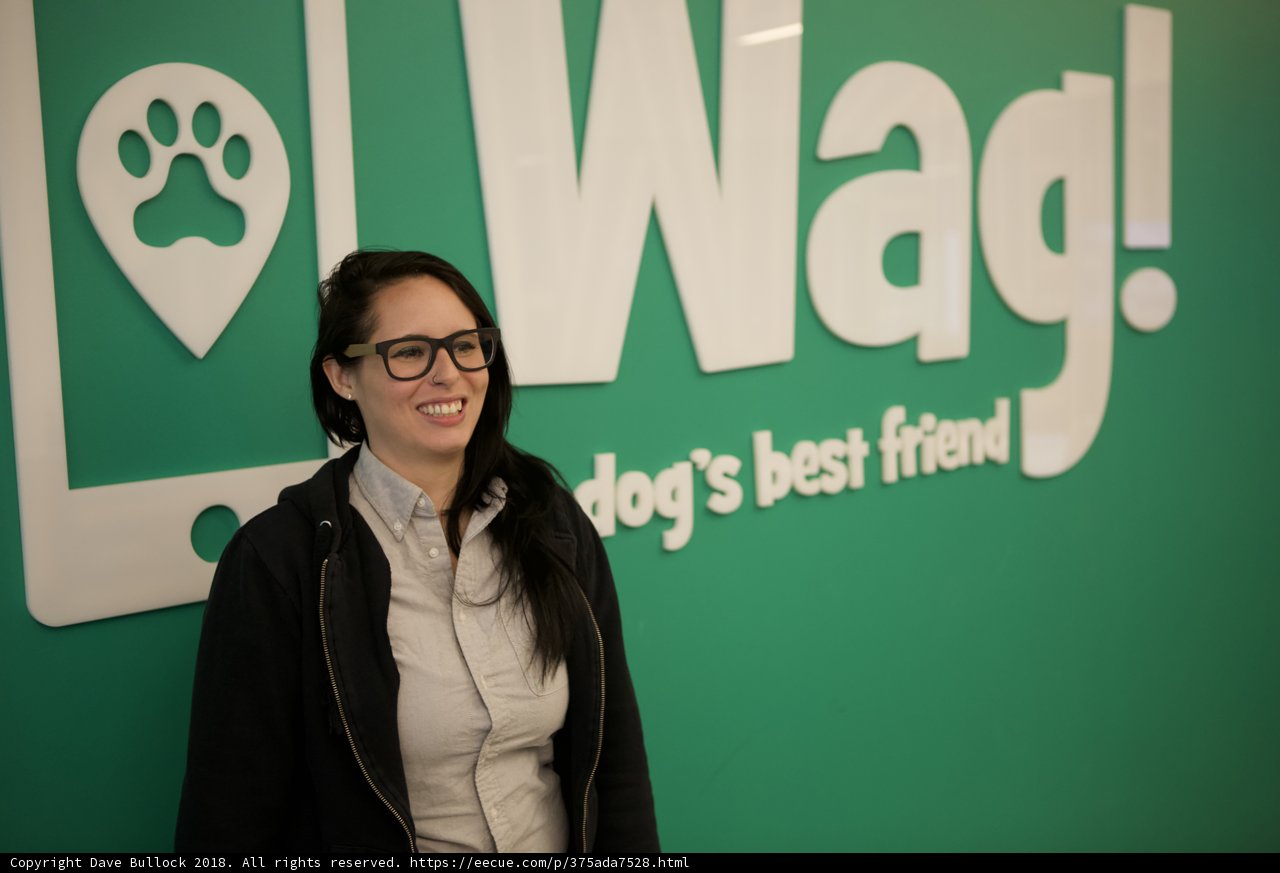 Smiling Woman Stands Proudly in Front of Wag Sign