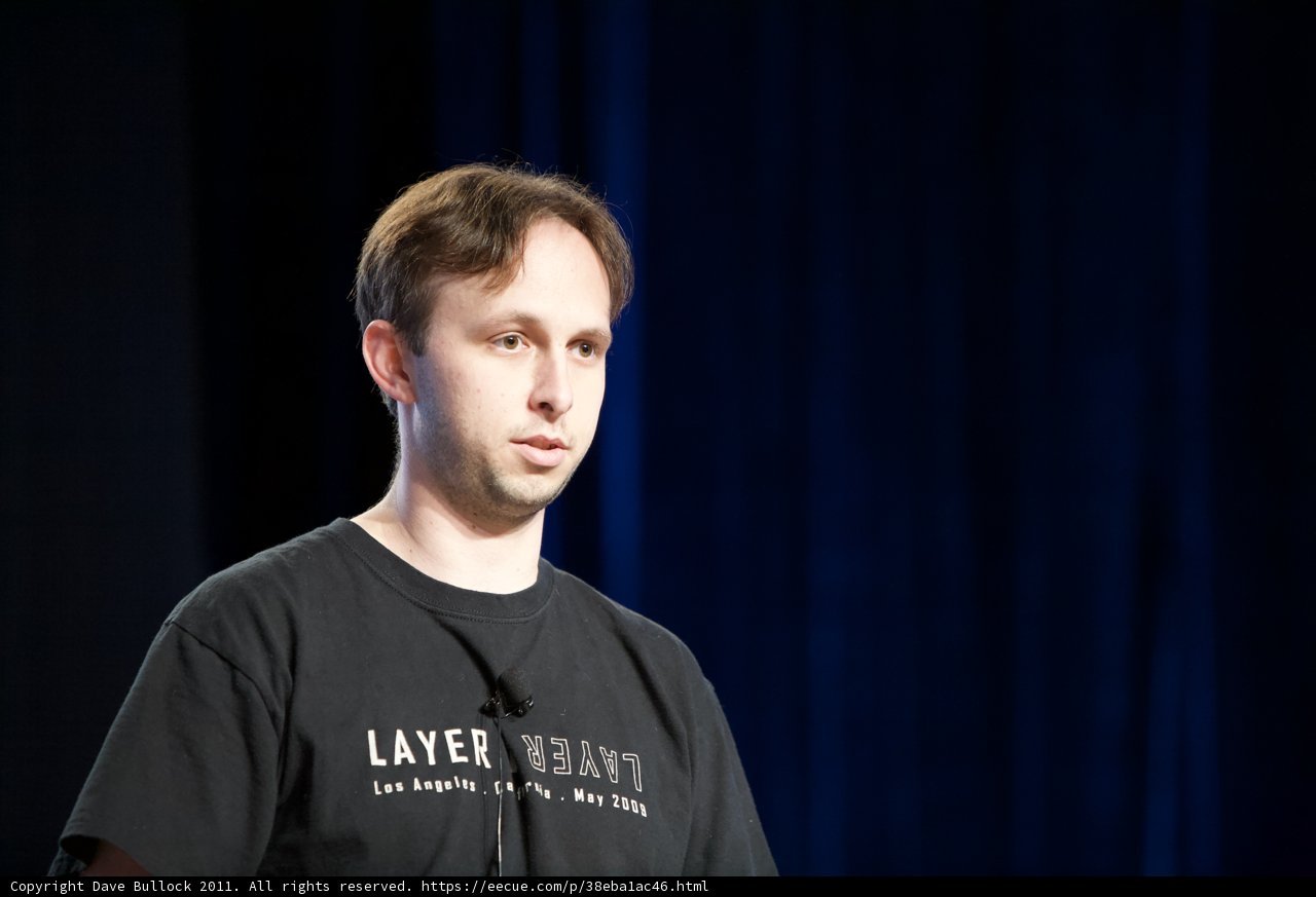 Man with Microphone in Black Shirt against Blue Background