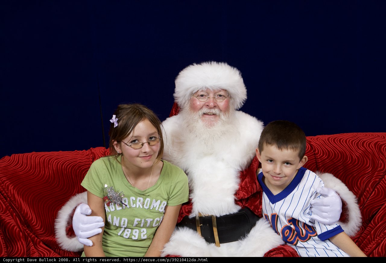 Santa Claus Spreading Holiday Cheer with Two Children on a Couch