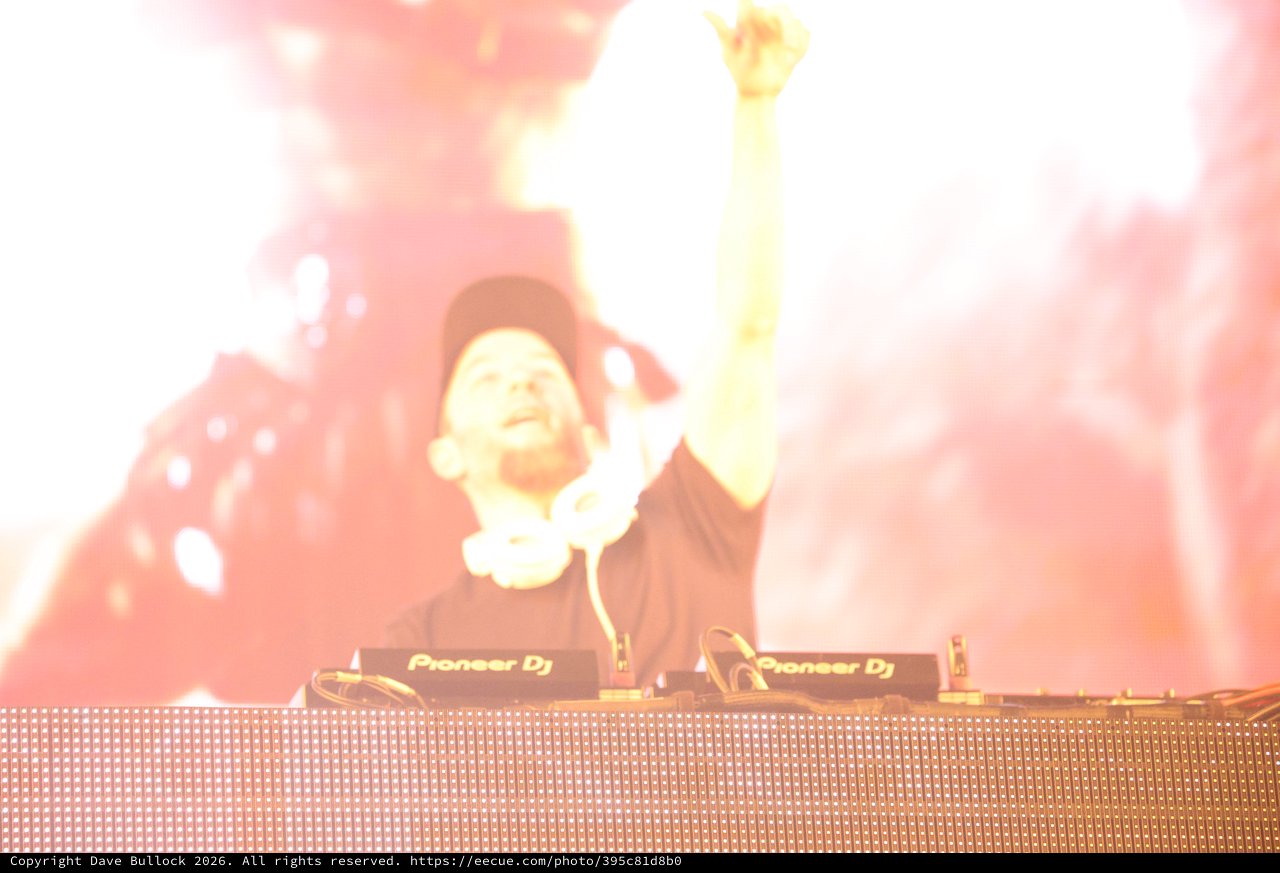 DJ Raises Hand Skyward Amid Explosive Stage Pyrotechnics