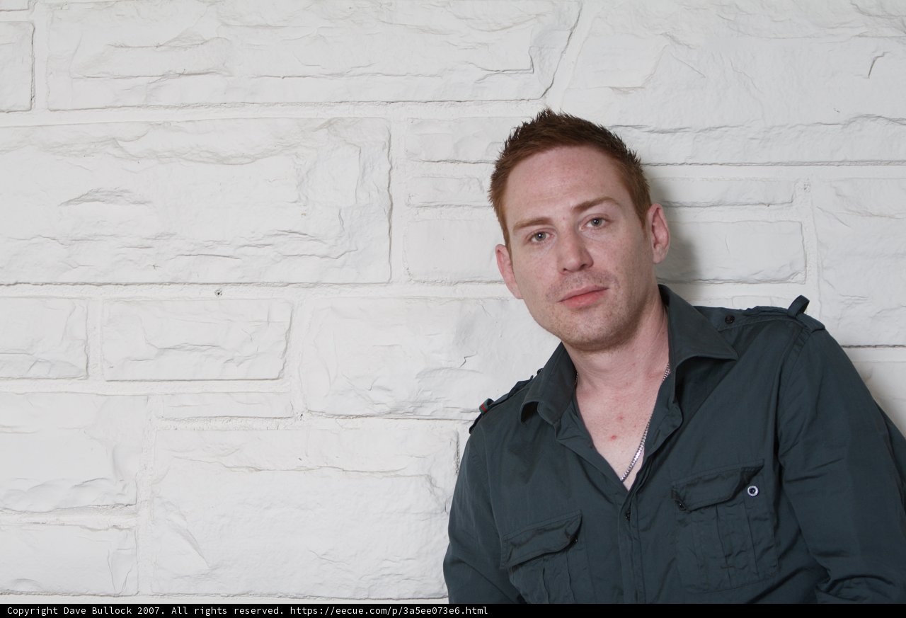 Green Shirted Man Contemplates Against Wall