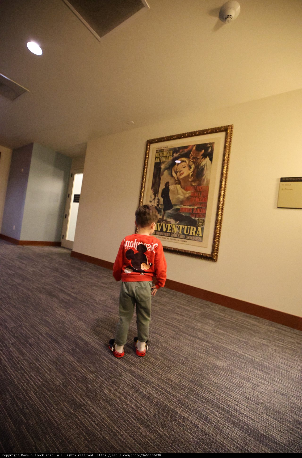 Child Admiring Vintage Film Poster in Hallway