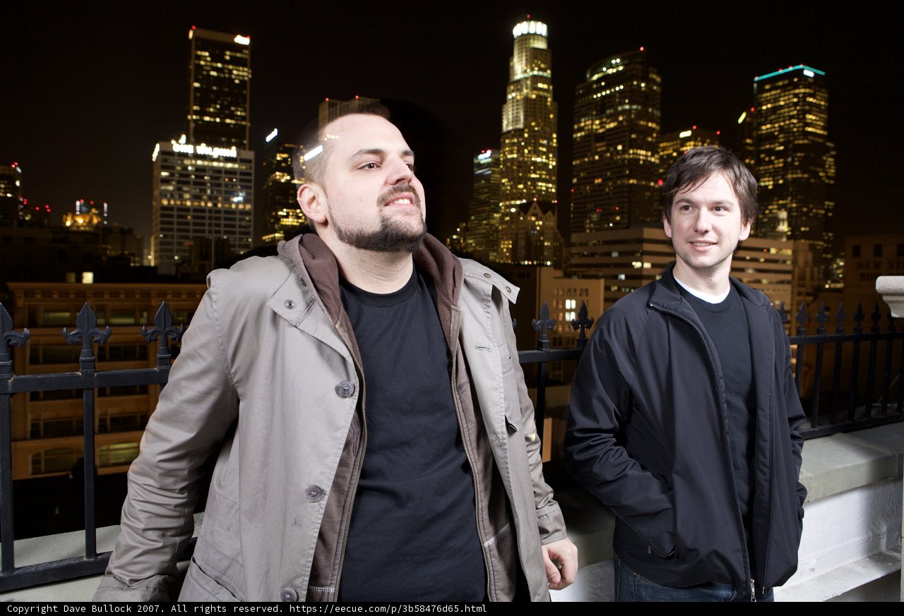 Two Men In Overcoats Against Metropolis Skyline