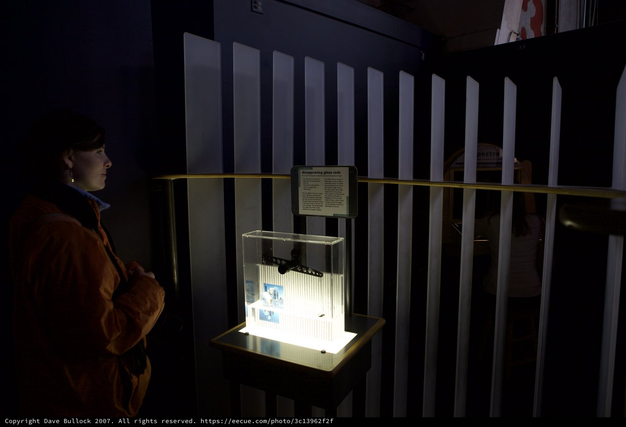 Curious Visitor Studies Disappearing Glass Rods Exhibit
