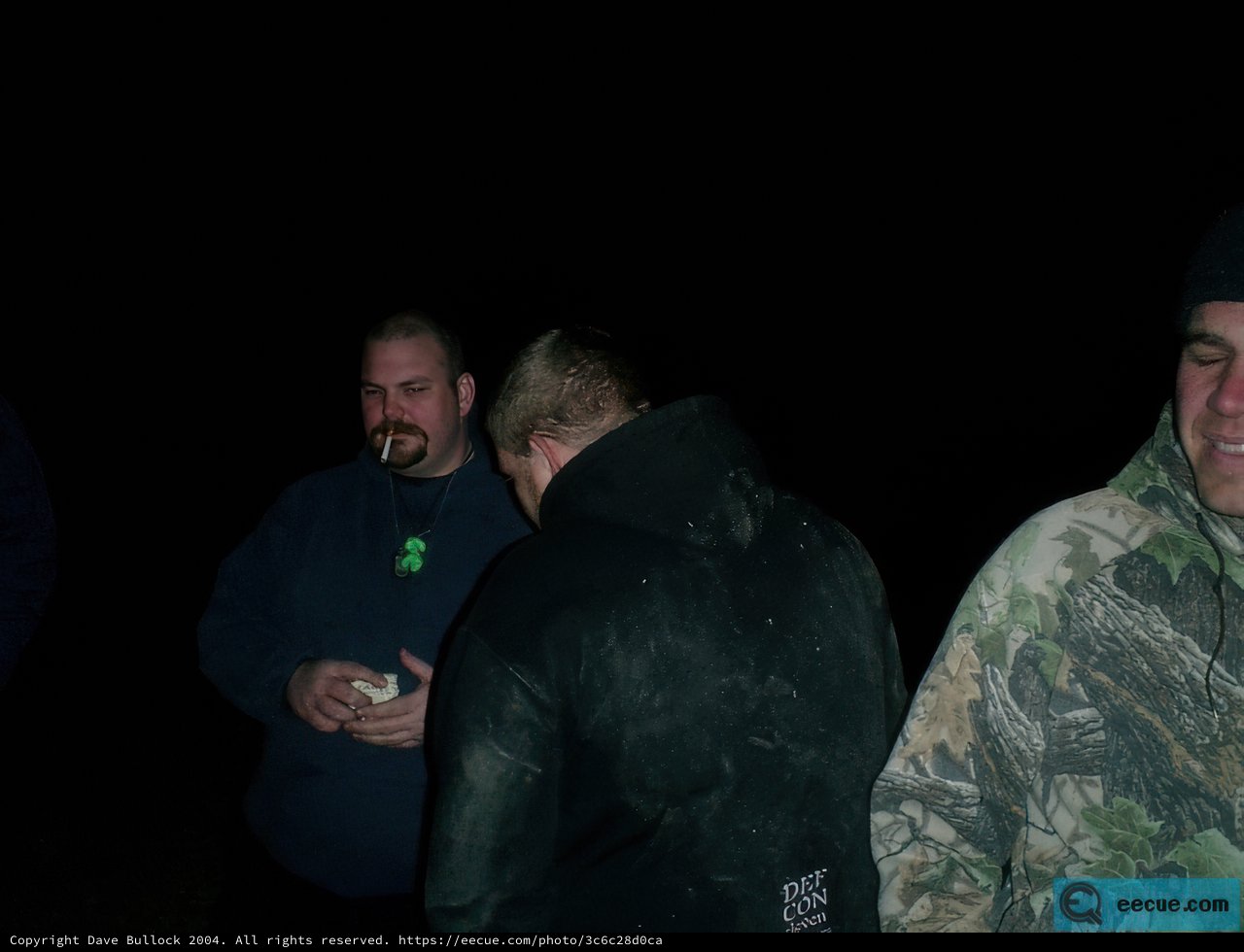 Three Men in Coats Holding Something in the Dark