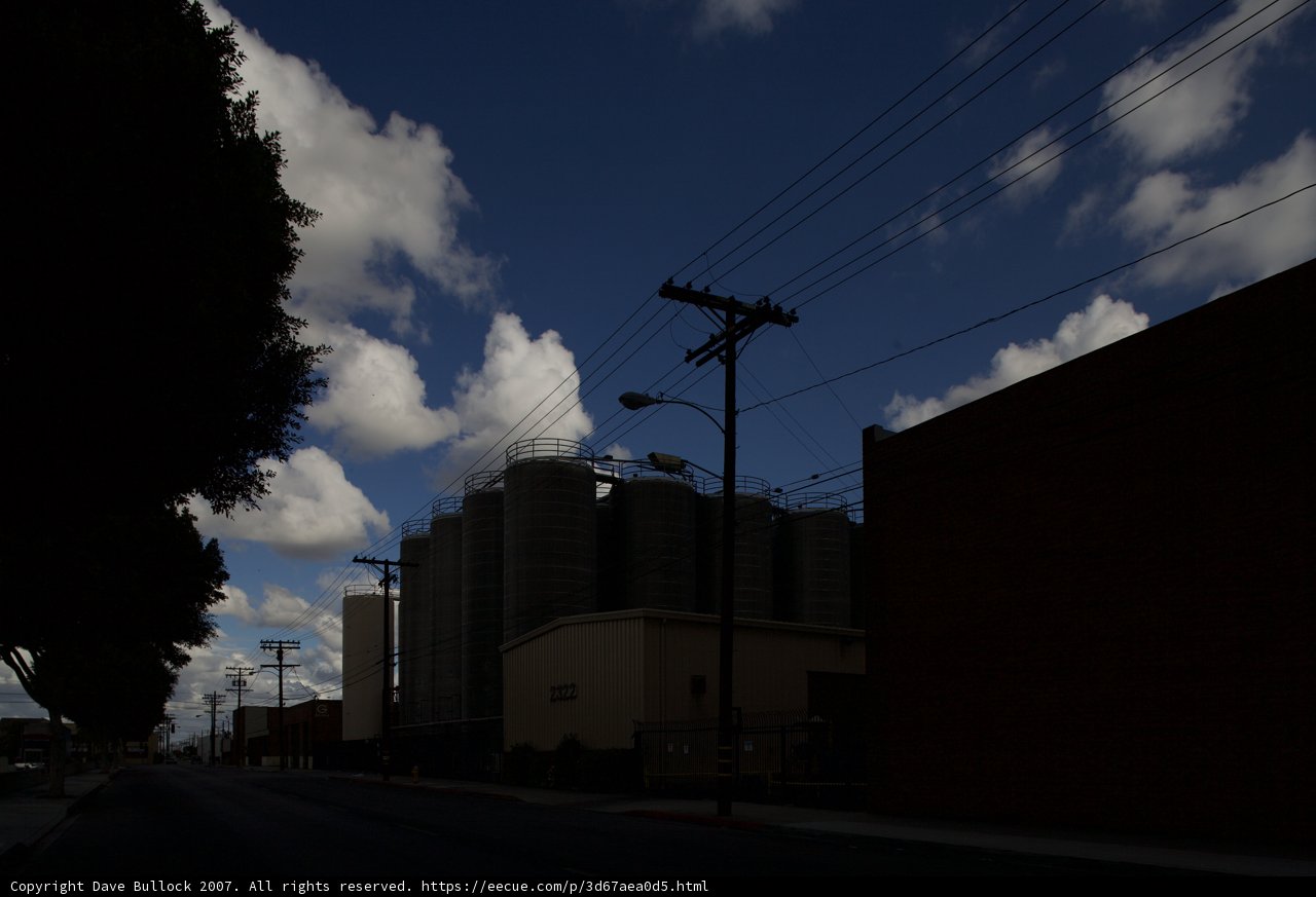 Urban Silhouette: Power Lines and an Office Building Against a Cloudy Sky