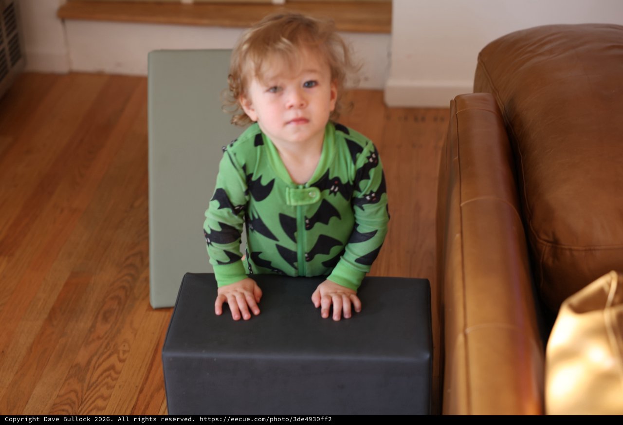 Curious Toddler in Green Dinosaur Pajamas at Home