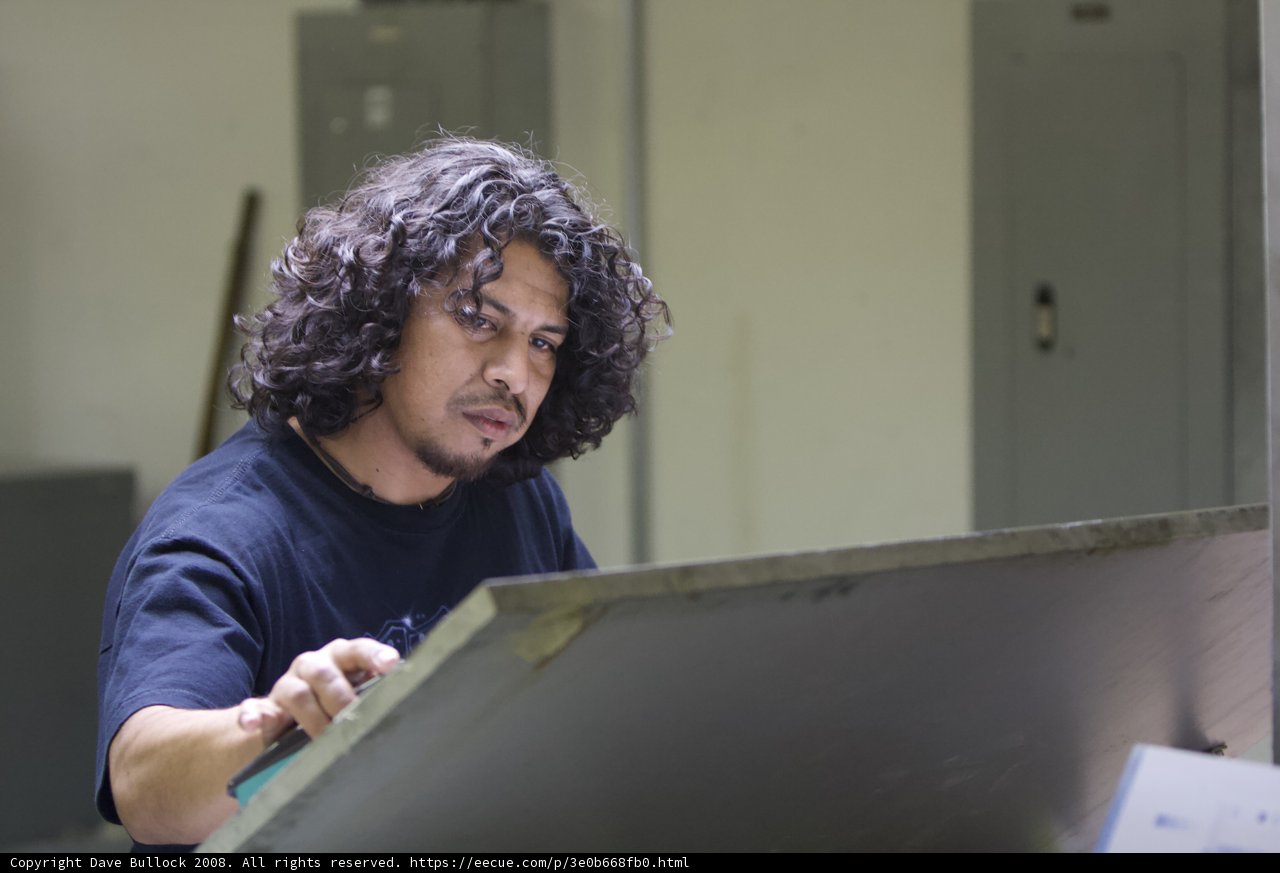 Curly Haired Man Working on a Metal Desk