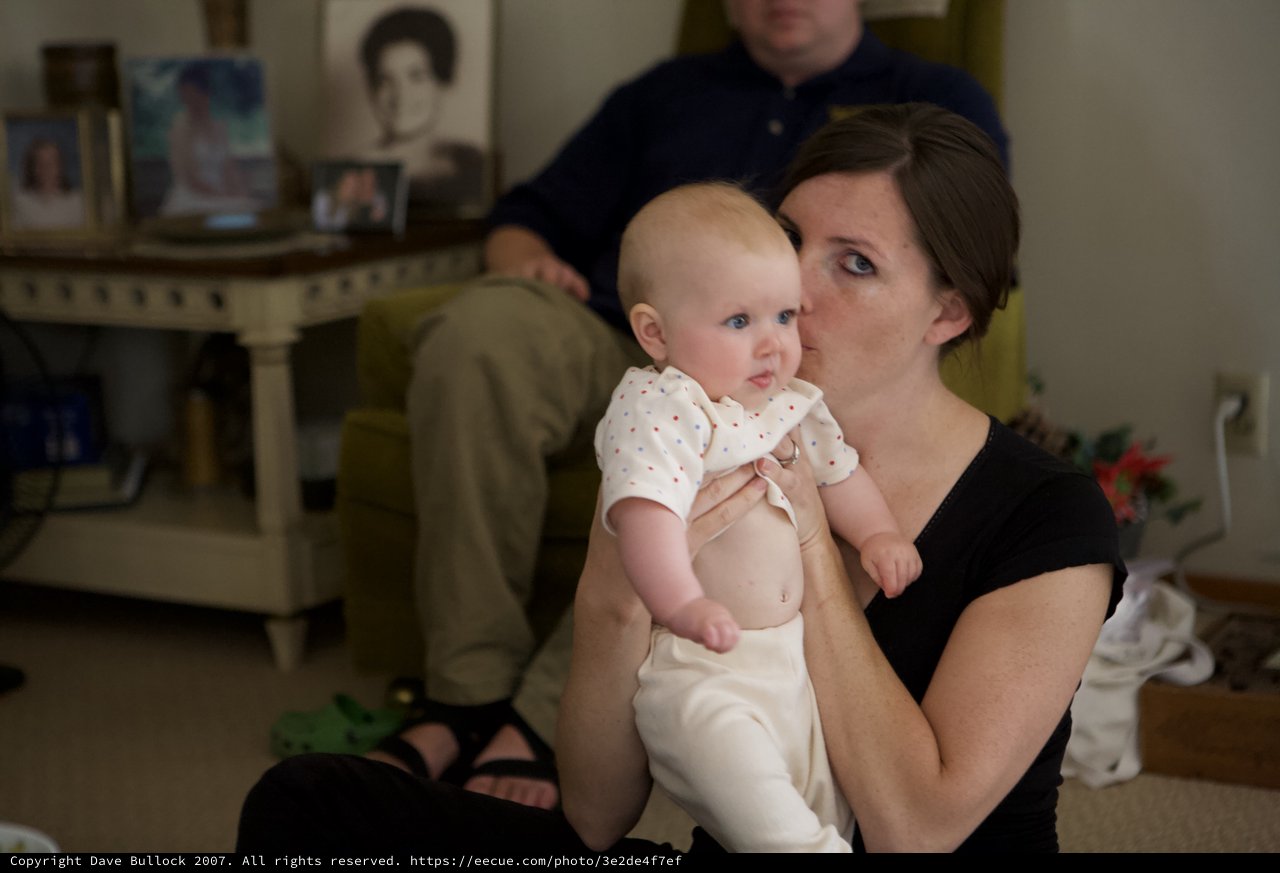 Mother Kisses Infant in Warm Family Living Room