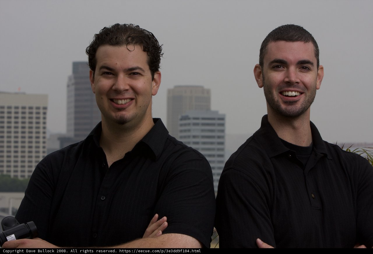 Two Happy Men in Black Shirts Pose for a Cityscape Portrait