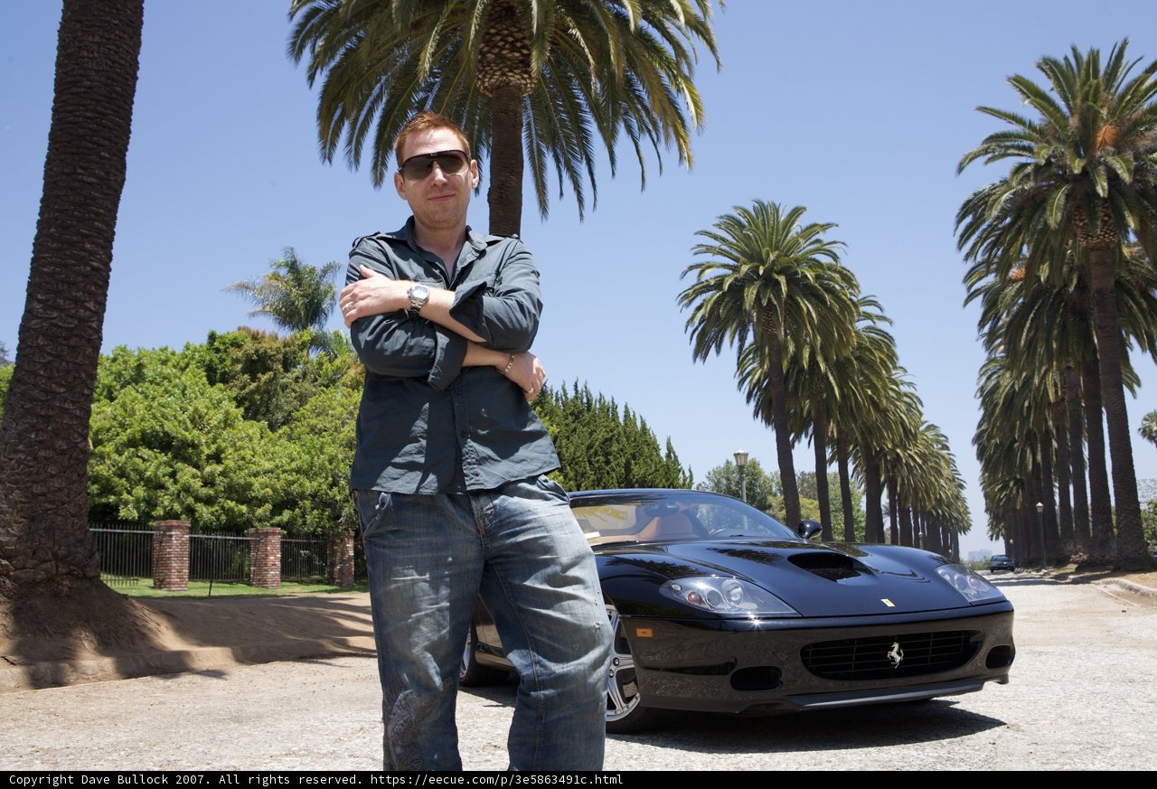 Man posing next to a luxurious Ferrari