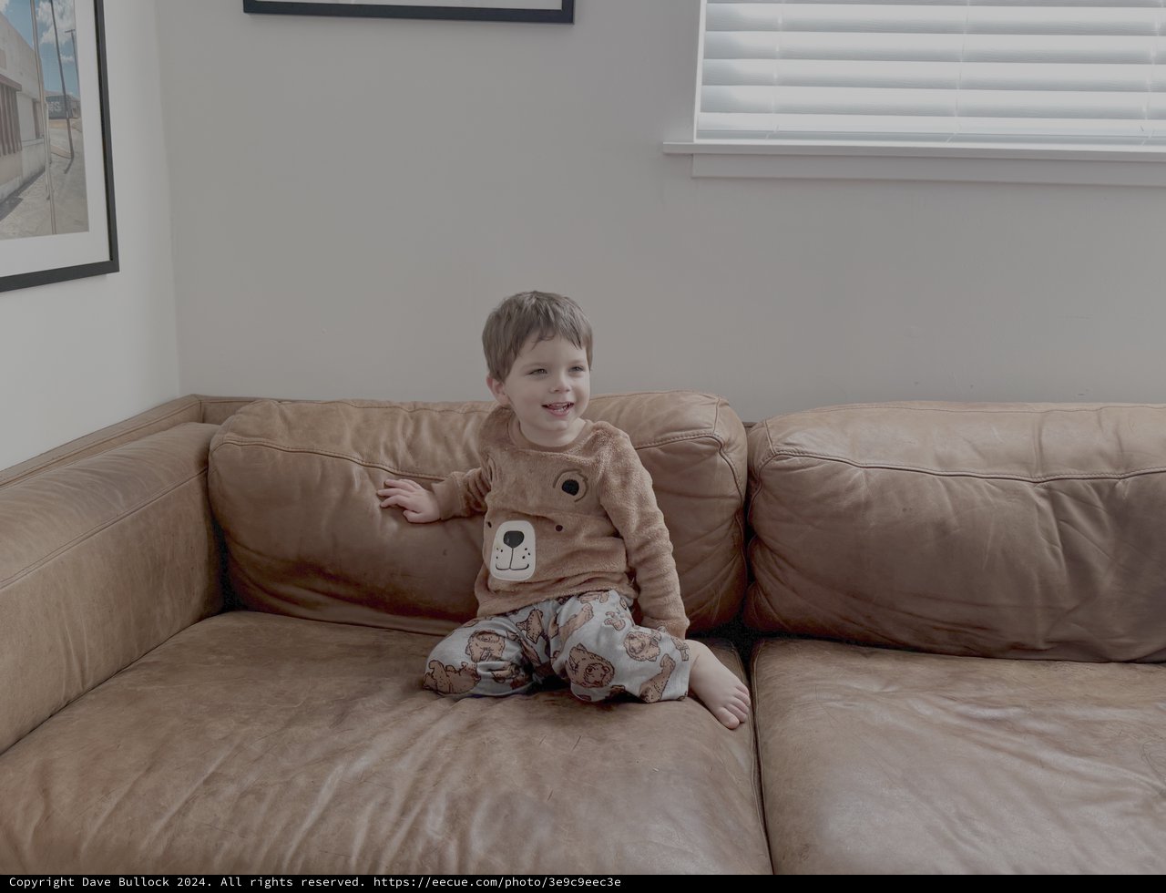 Happy Child in Bear Pajamas on Couch