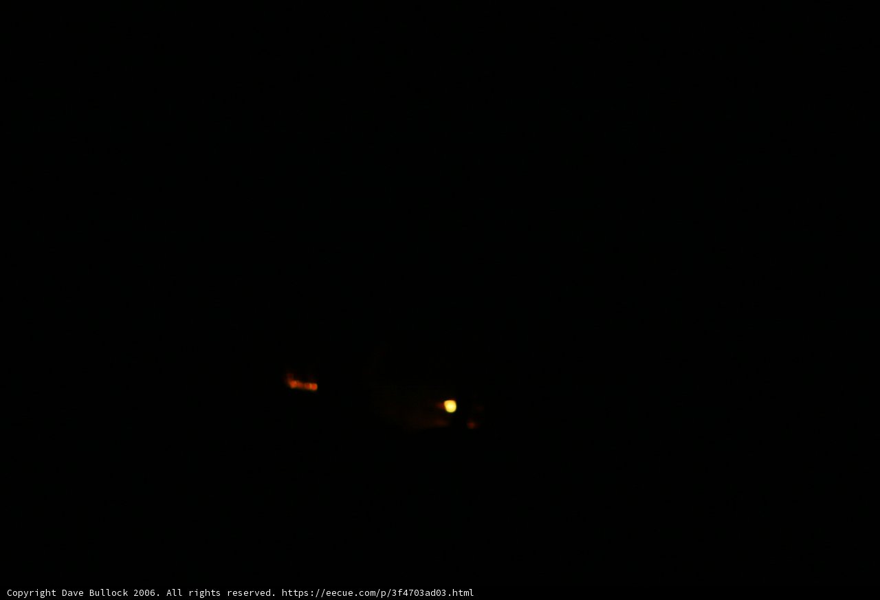 Illuminating the Night Caption: A glimmer of hope shines in the distance amidst a fiery night sky.