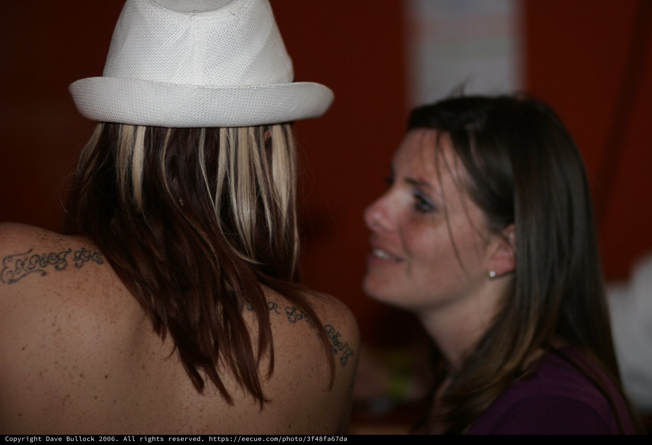 Tattooed Woman in White Fedora Shares a Moment
