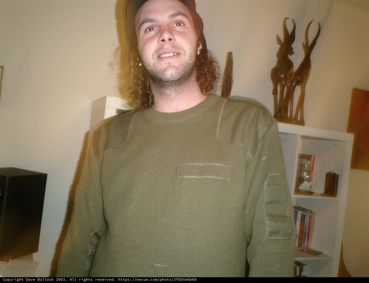 Green Shirted Tal c Poses for Portrait Amidst Bookshelves