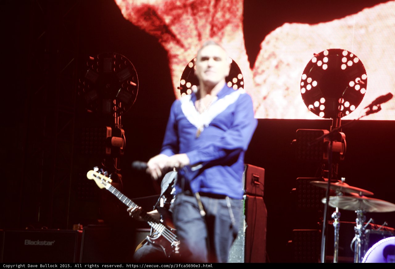 Morrissey Singing Blue Shirt Bassist Behind Two Circular Lights Blackstar Drums Red Screen
