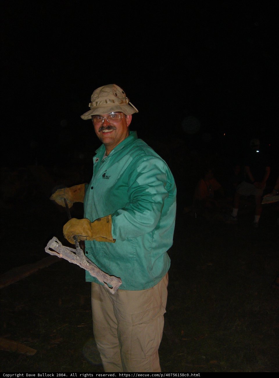 Man in Green Hat and Shirt Holds Wooden Plank