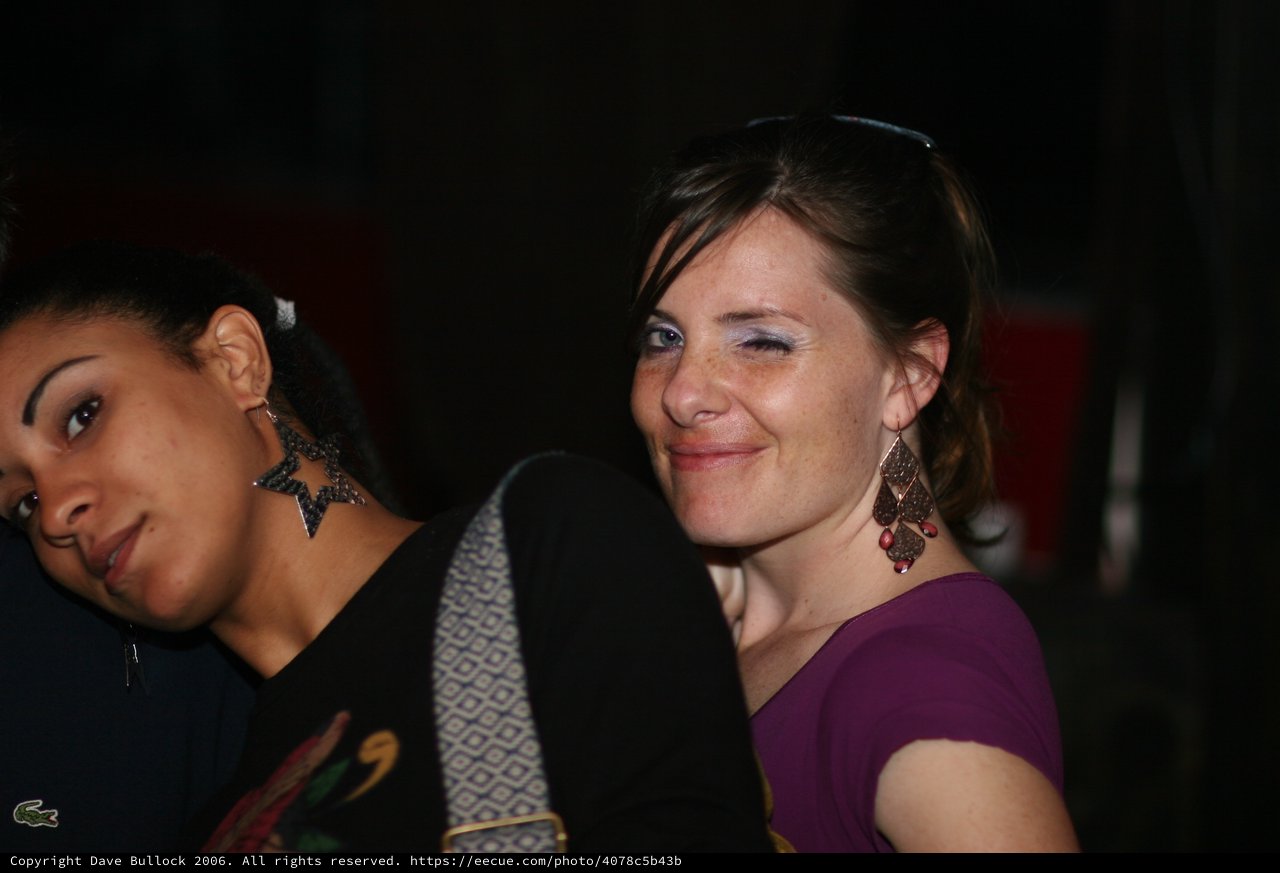 Two Women Smiling at a Nighttime Social Gathering