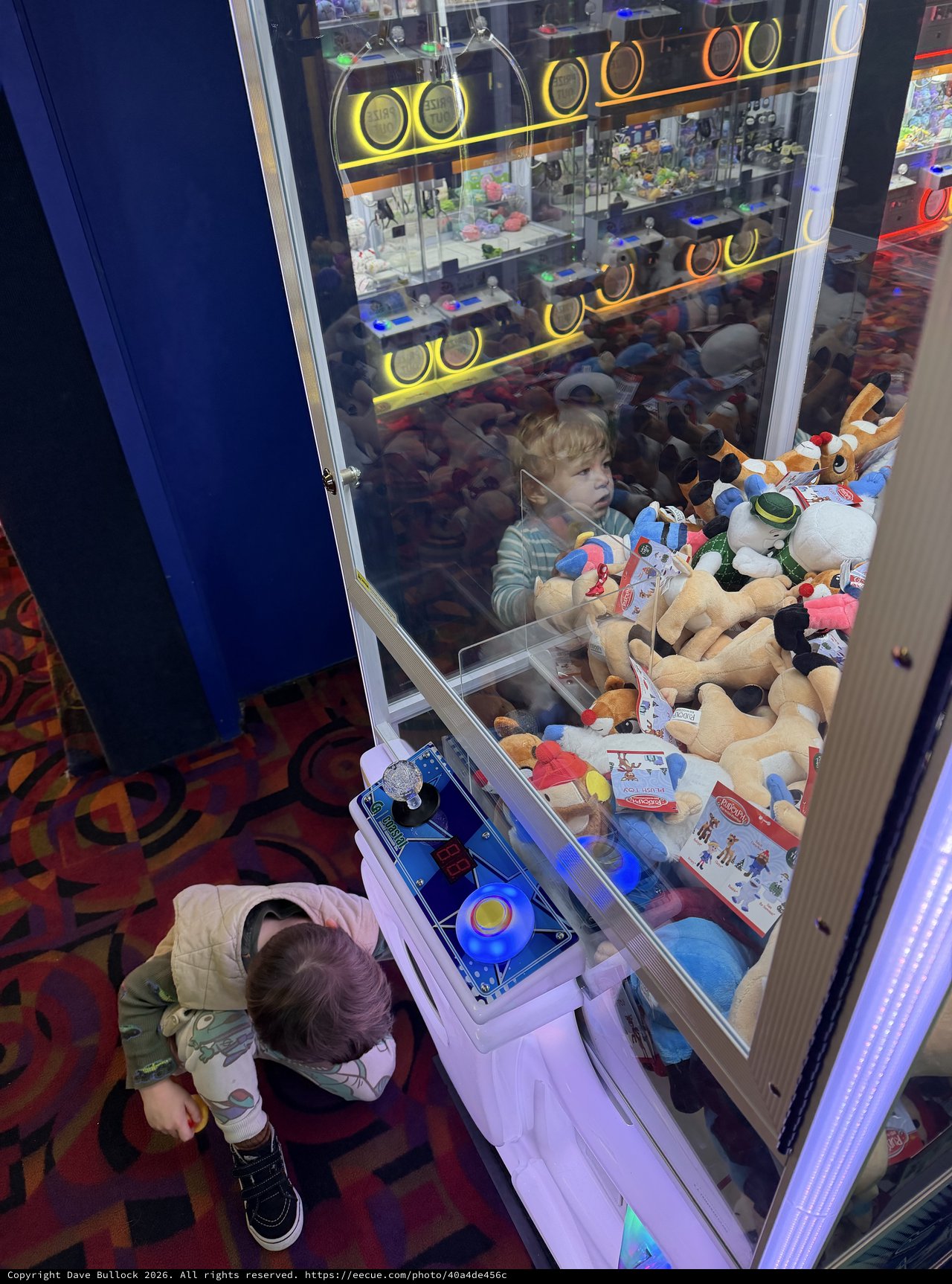 Child Playing Claw Machine Game at Arcade