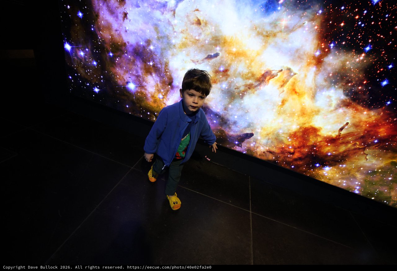 Child Exploring Cosmic Nebula Display at Space Center