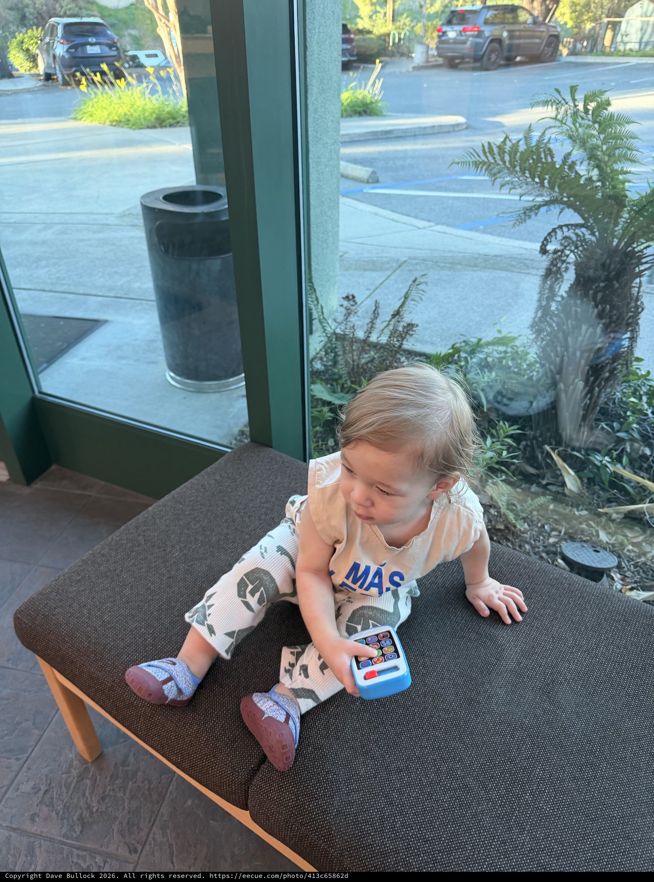 Toddler Playing with Toy Phone in Modern Cafe