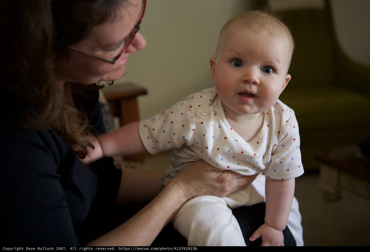 Bright-Eyed Baby Supported by Caring Mother