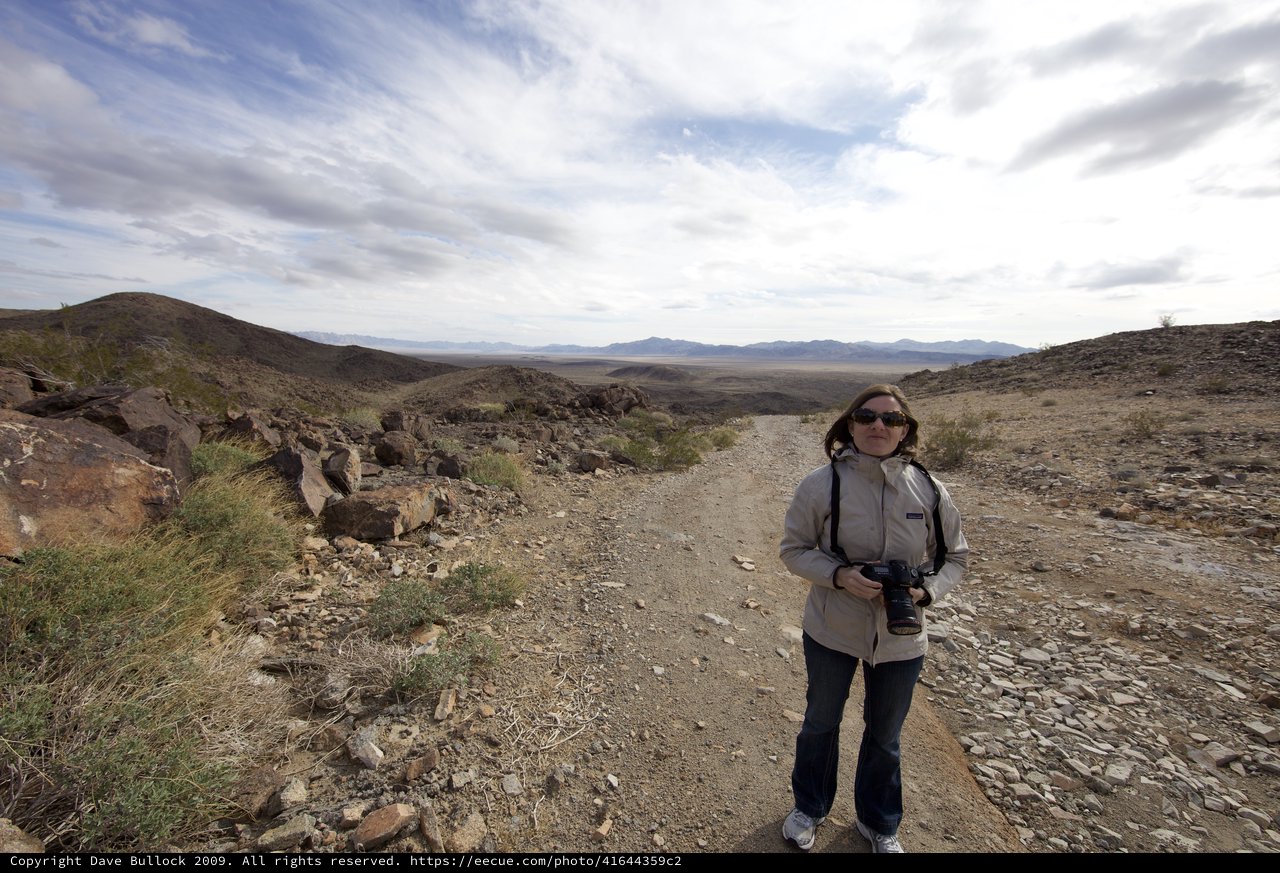 Photographer Stands on Desert Ridge Trail Overlooking Valley