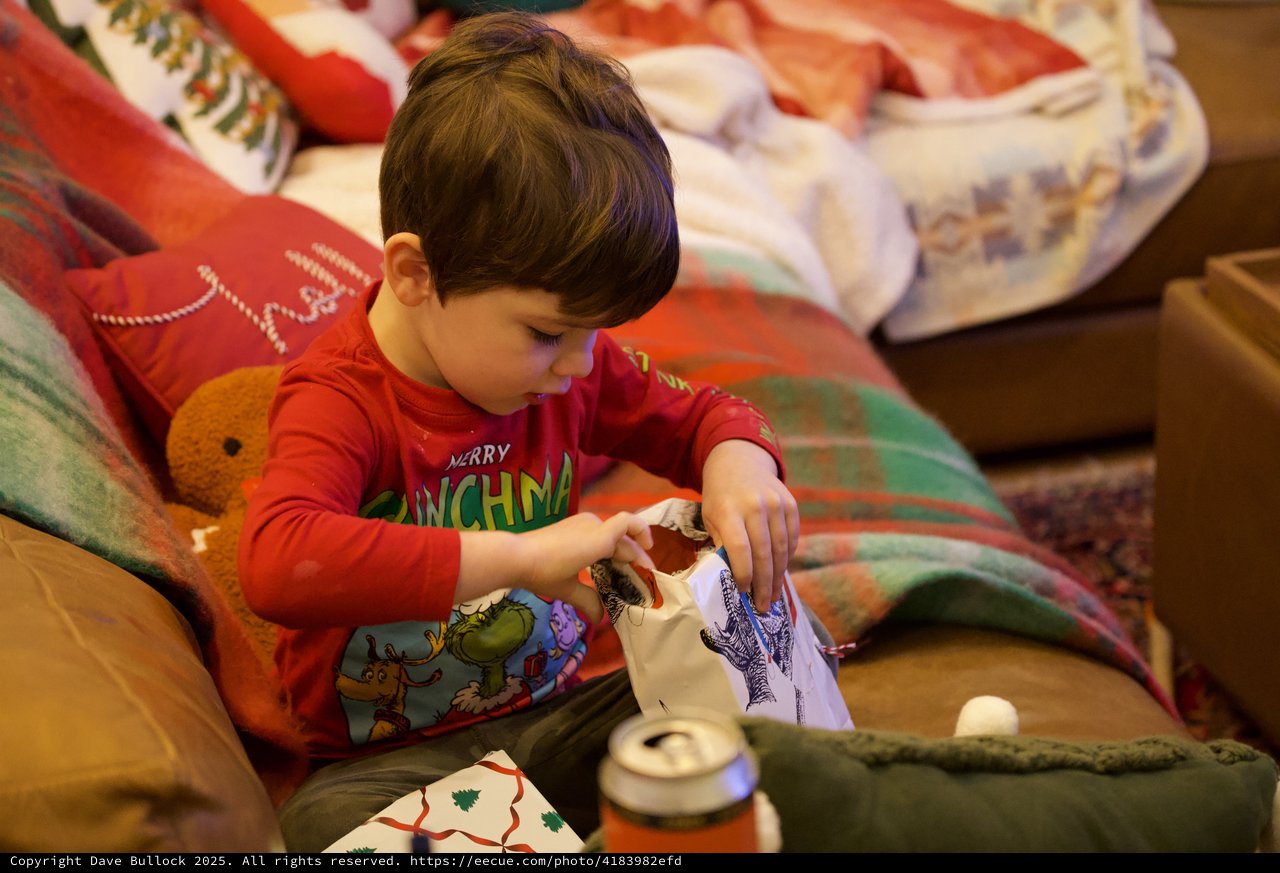 Young Child Opening Christmas Presents in Cozy Living Room