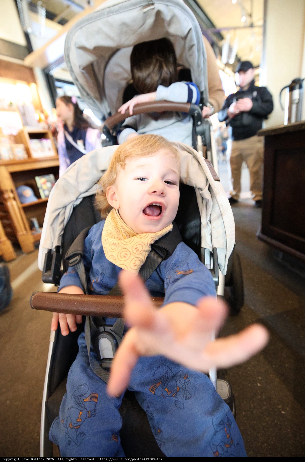 Joyful Child Reaching Out in Double Stroller