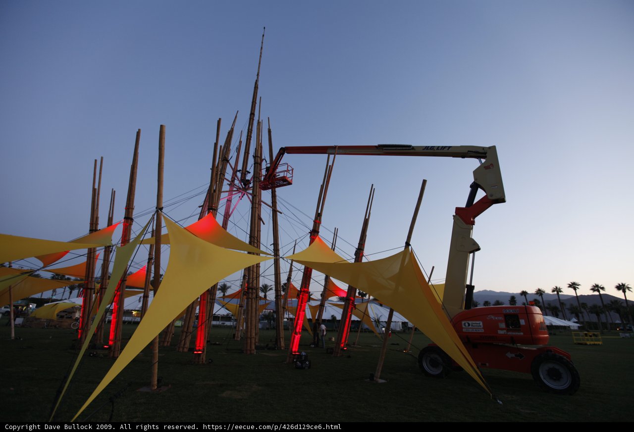 Crane lifting a large structure with flags at Coachella