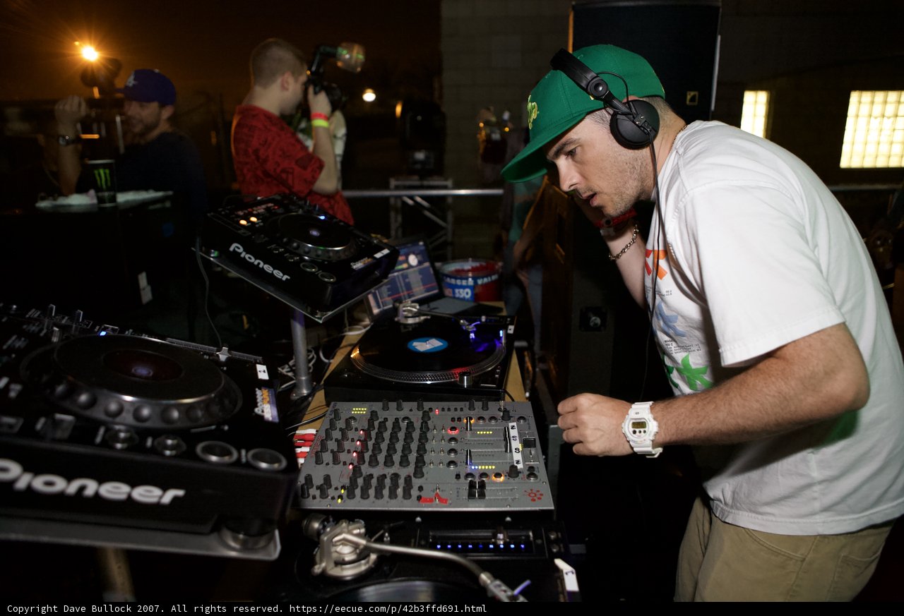 Green-Hatted DJ Mixing Music with Headphones