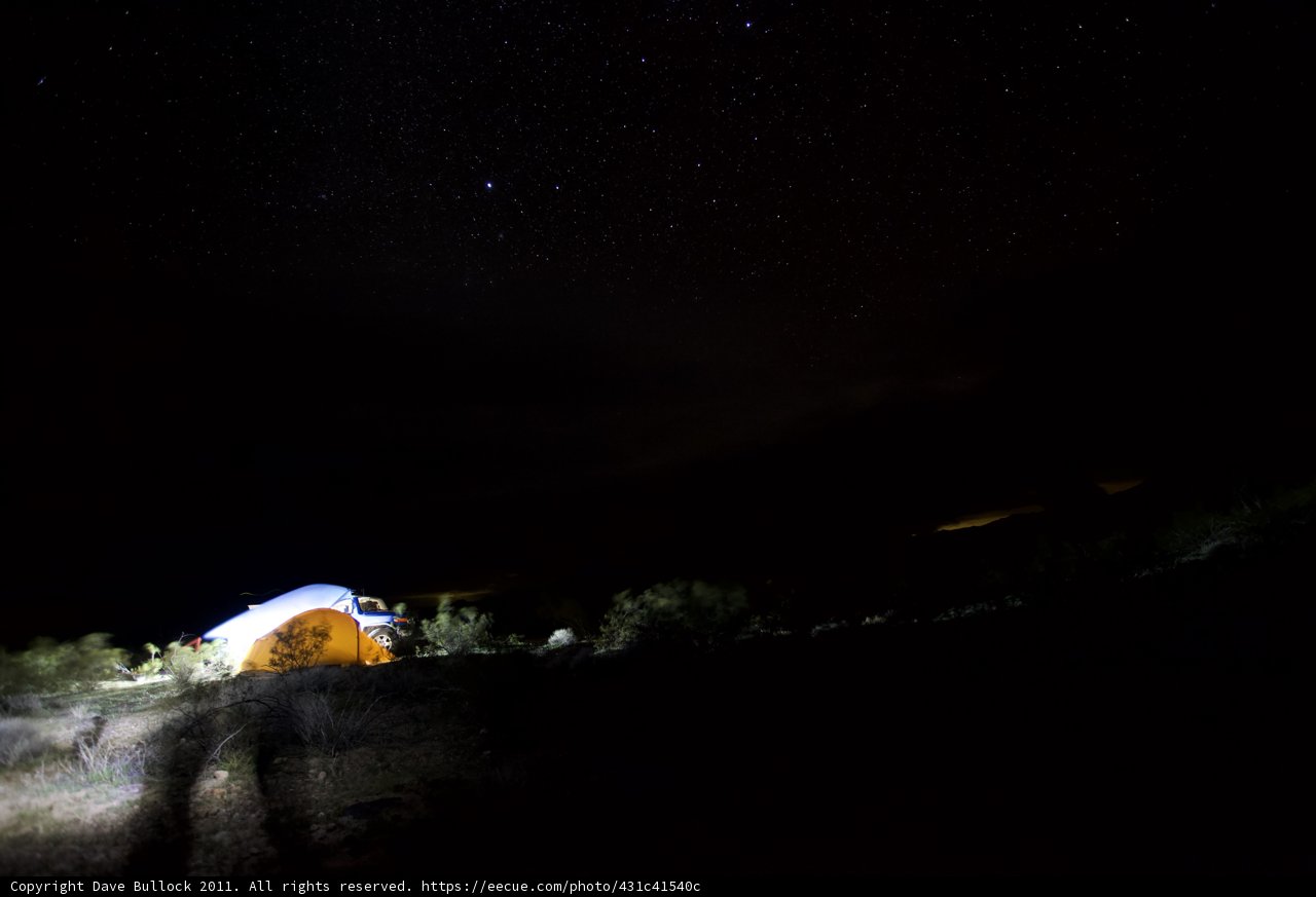 Mountain tent under the starry sky Caption: A cozy camping night under the stars, with a lit up mountain tent providing the perfect shelter for outdoor enthusiasts.