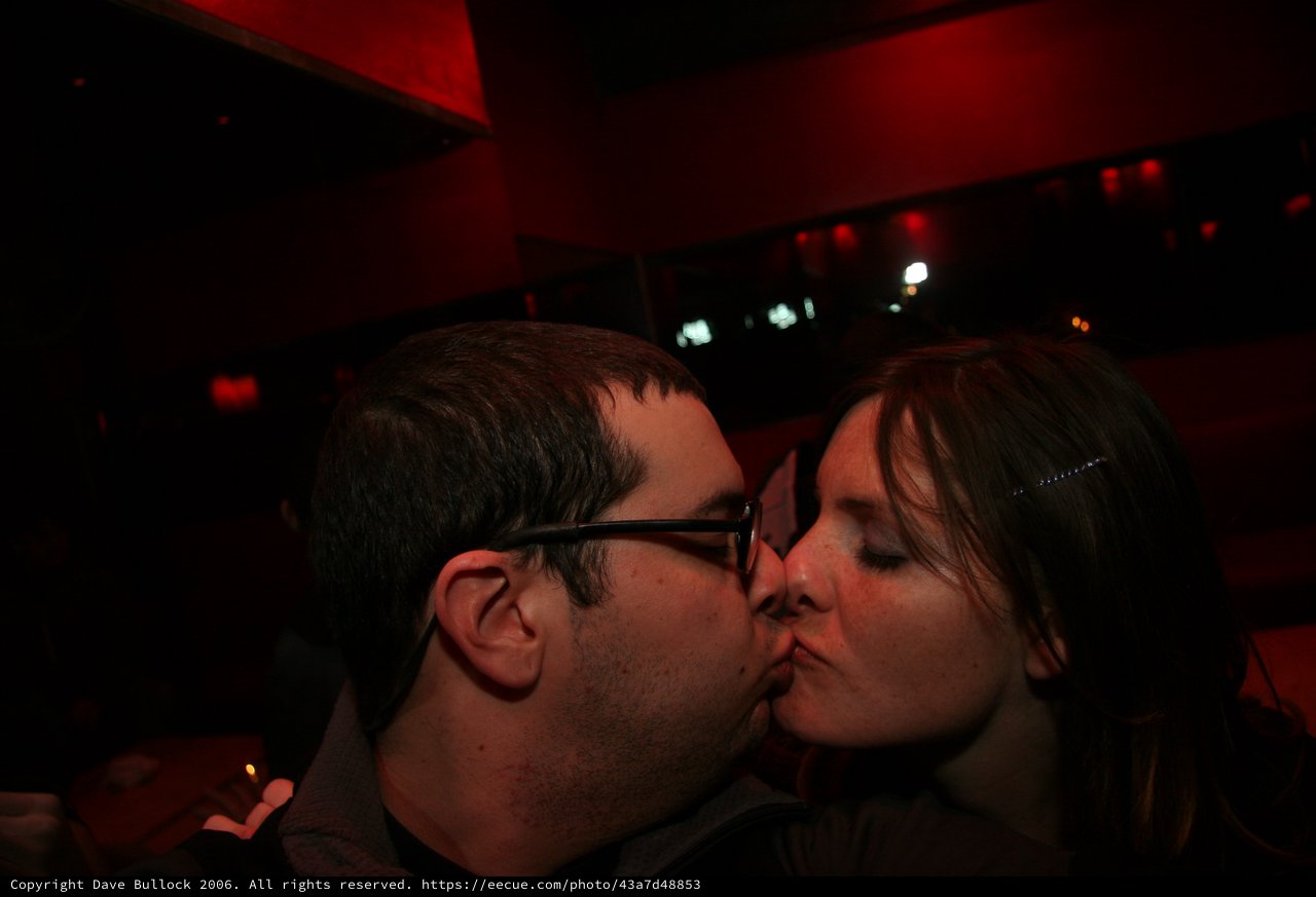 A Couple Sharing a Kiss at a Dimly Lit Bar