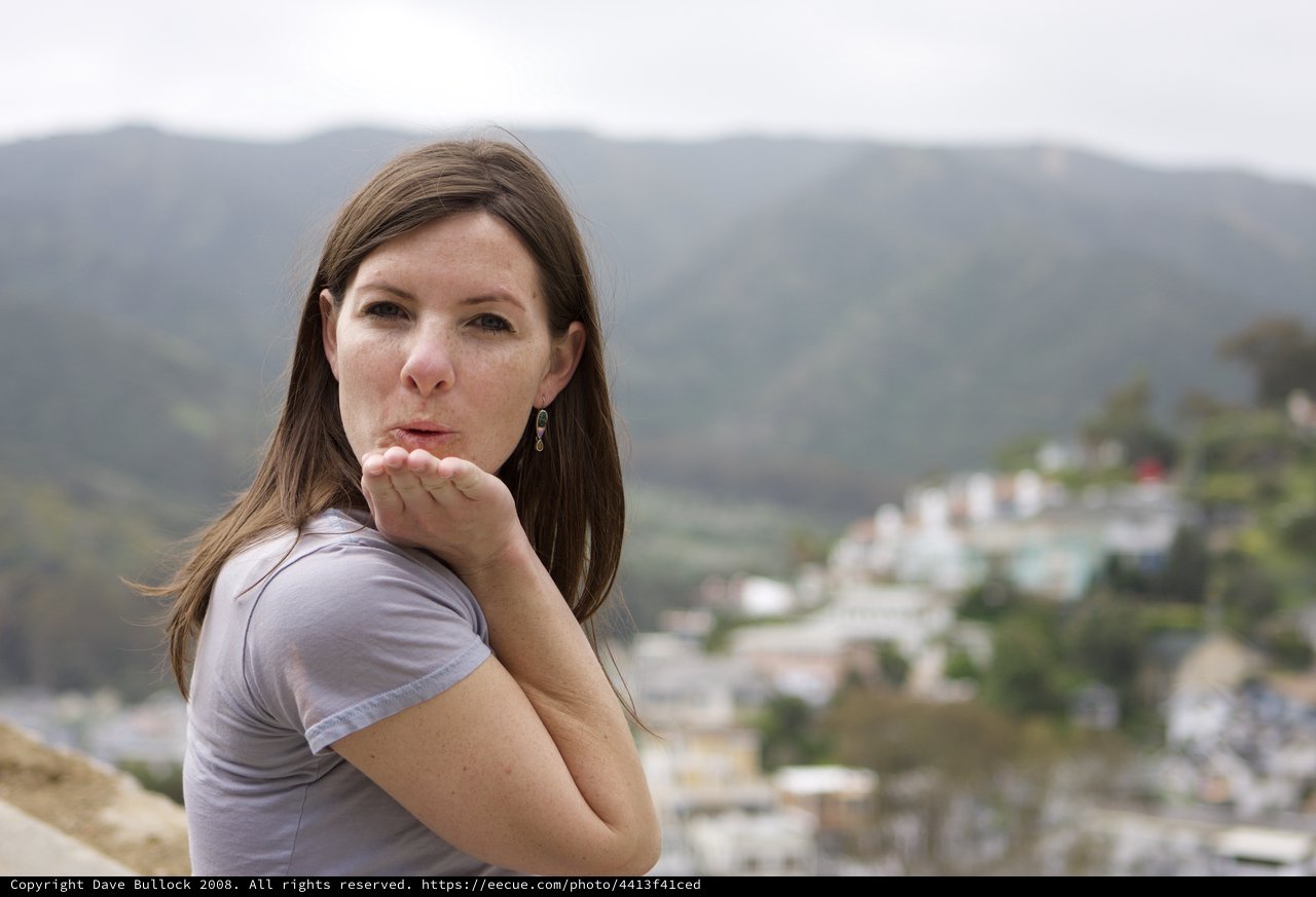 Woman Blowing a Kiss Over Hillside Town