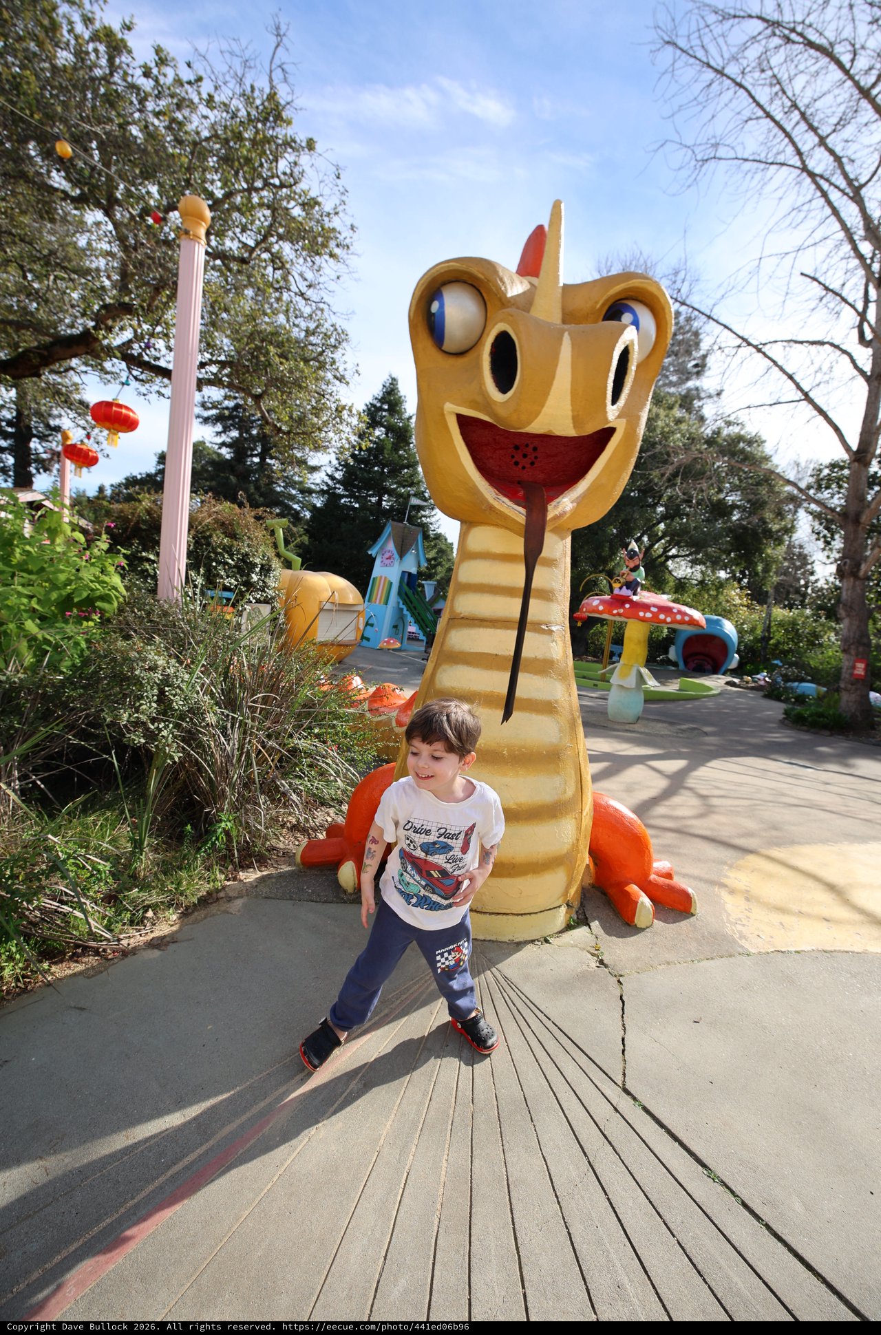 Young Boy Walking Past Giant Dragon Slide at Theme Park