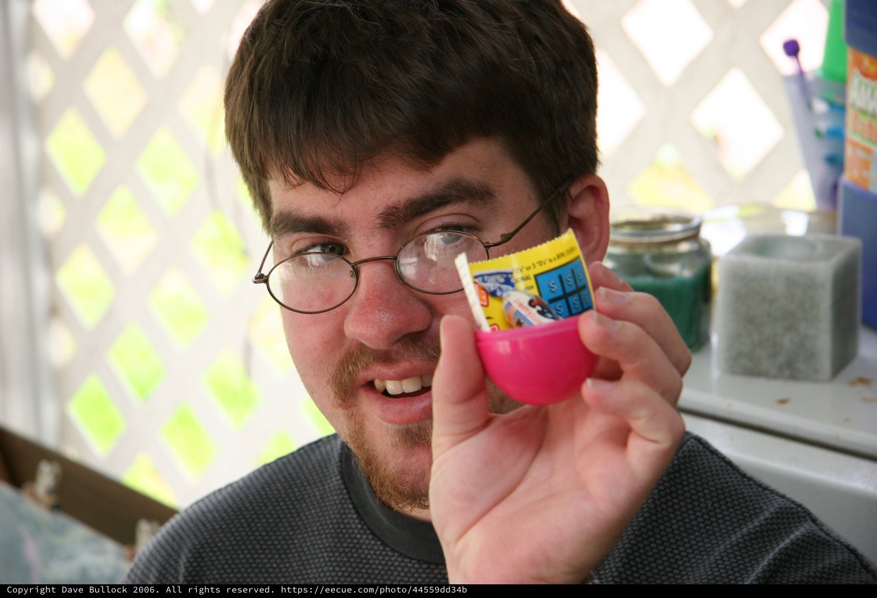 Young Man Examines Tiny Prize from Plastic Capsule