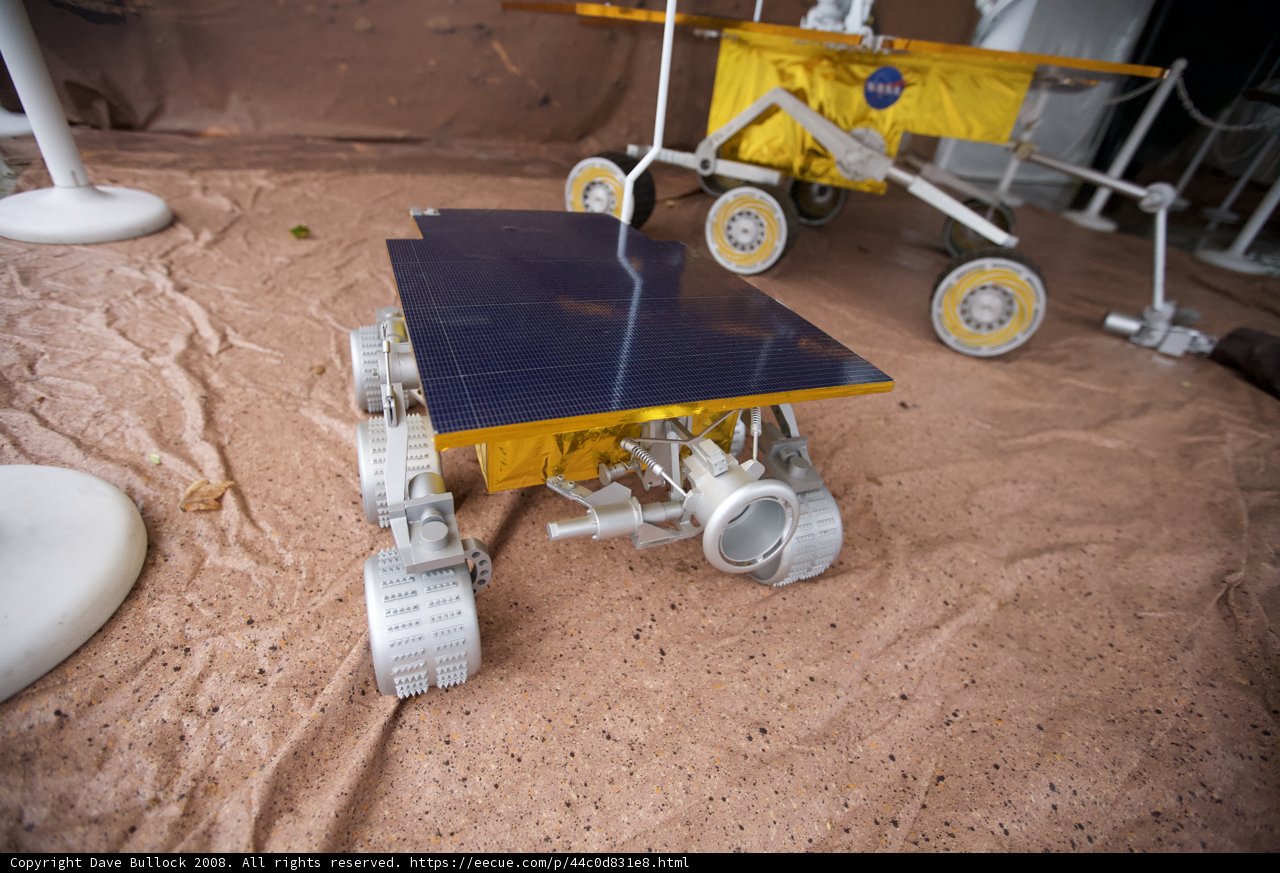Model Rover with White Object on Plywood Ground