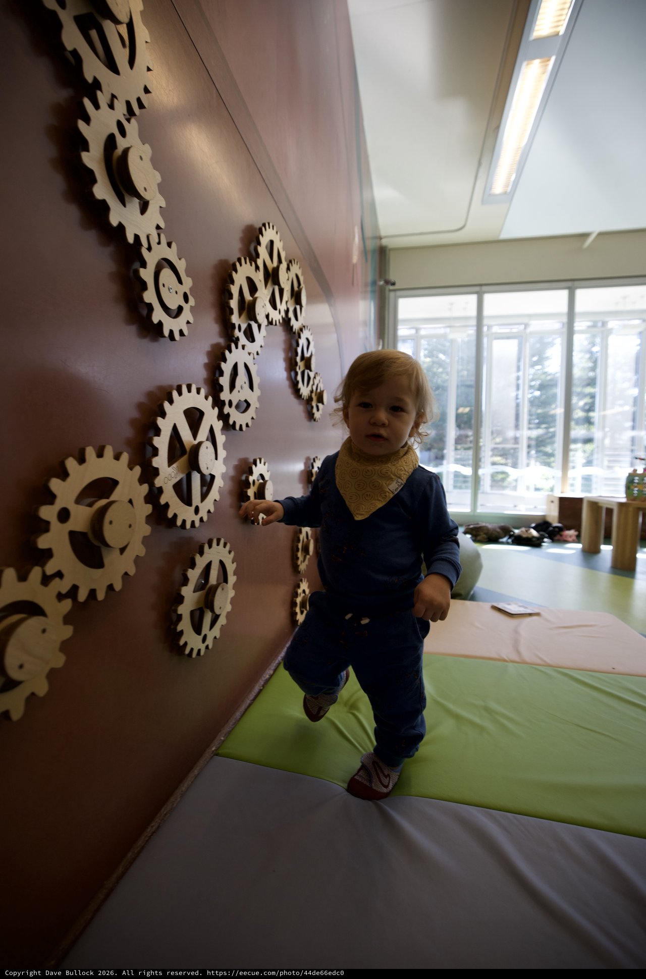 Toddler Playing on Interactive Gear Wall Installation