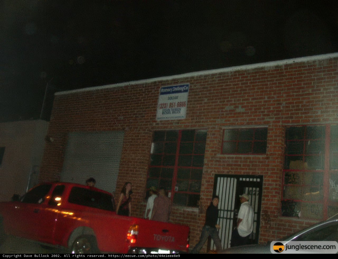 Red Pickup Truck Parked Outside Brick Building at Night