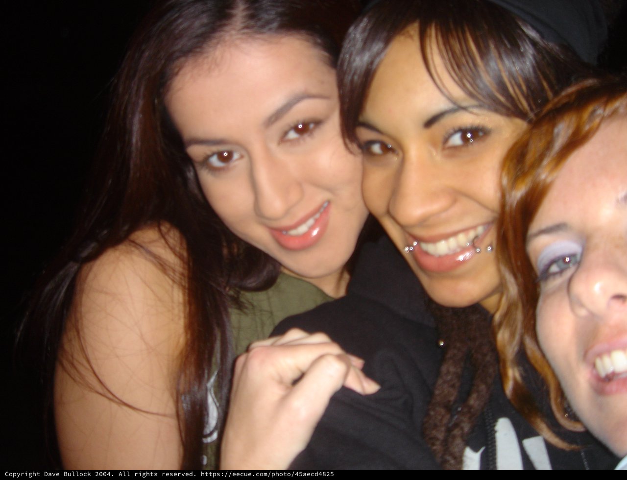 Three Friends Smiling Together at a Nighttime Event