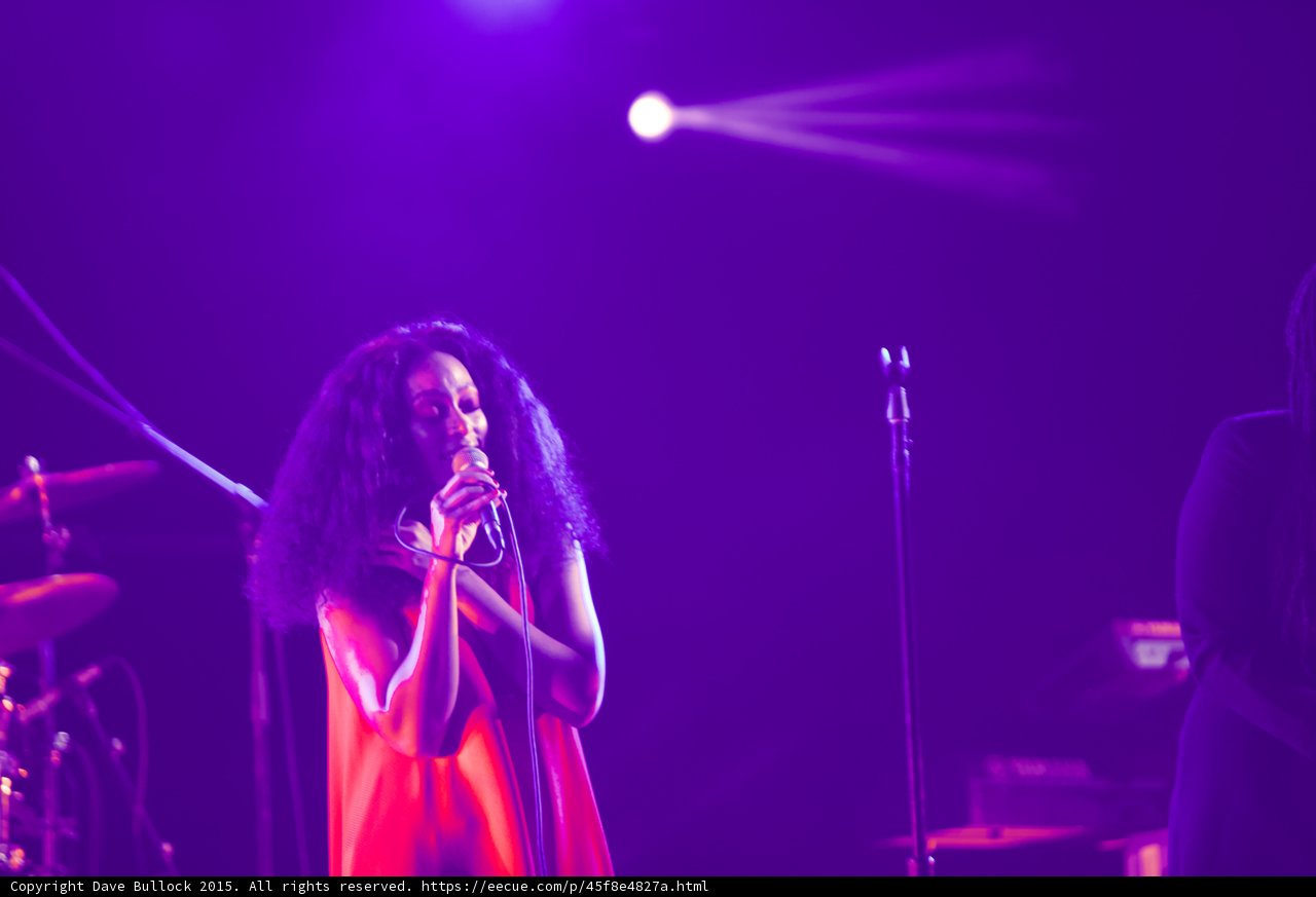 Solange Portrait Red Dress Hands Clasped Mic Curly Hair Spotlight Purple