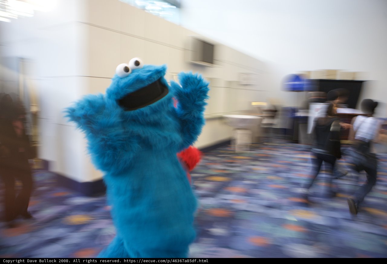 Blue Cookie Monster Mascot Poses with Three People at 2008 NAMM Event