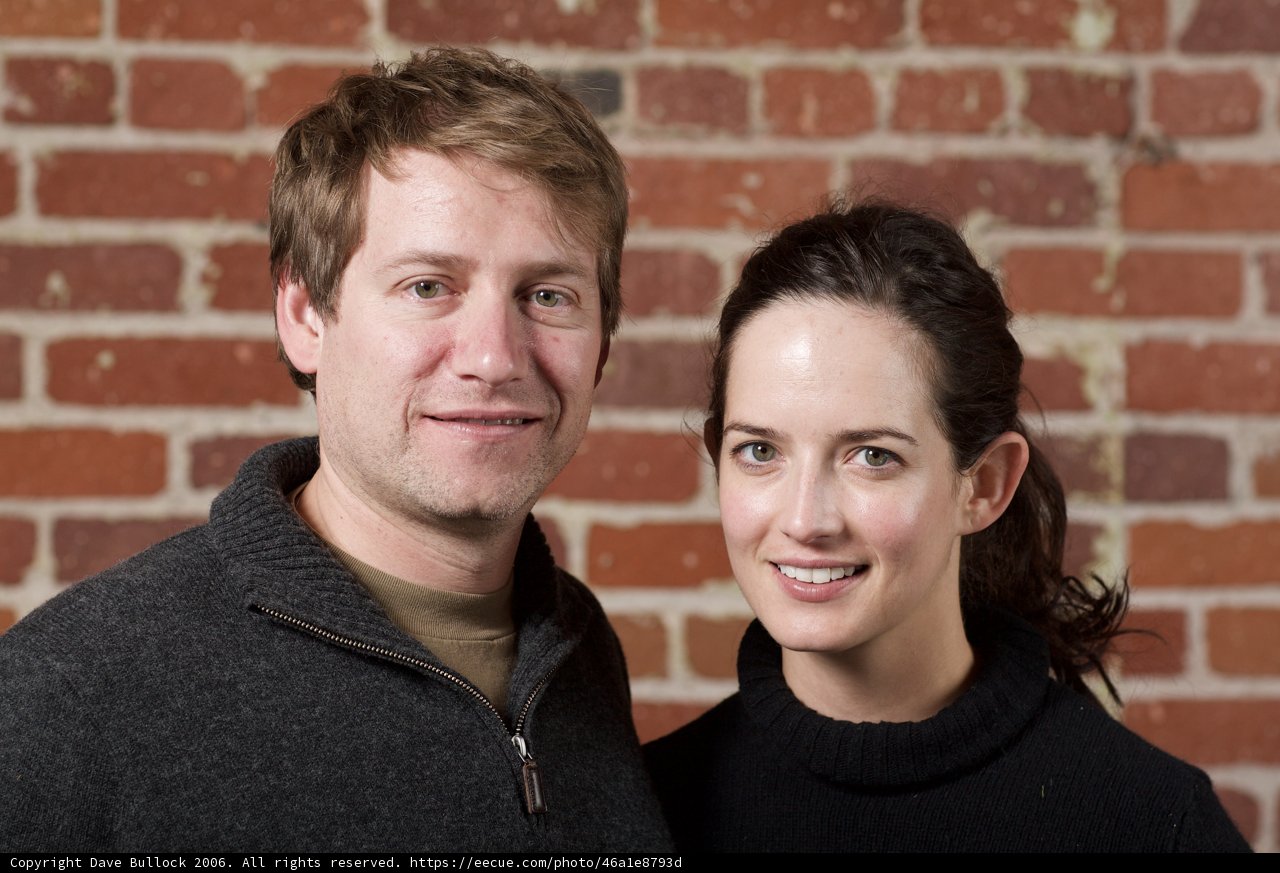 Smiling Couple Poses in Front of Brick Wall