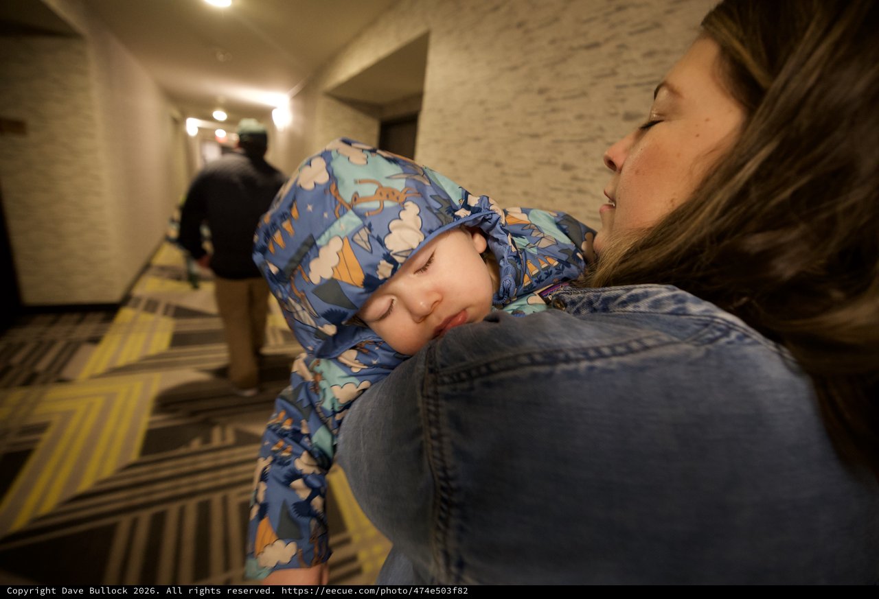 Sleeping Child Carried Through Hotel Hallway at Night