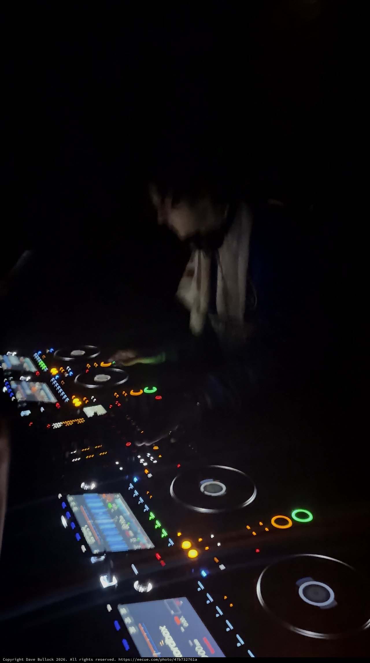 DJ Performing in Dark Nightclub with Illuminated Equipment