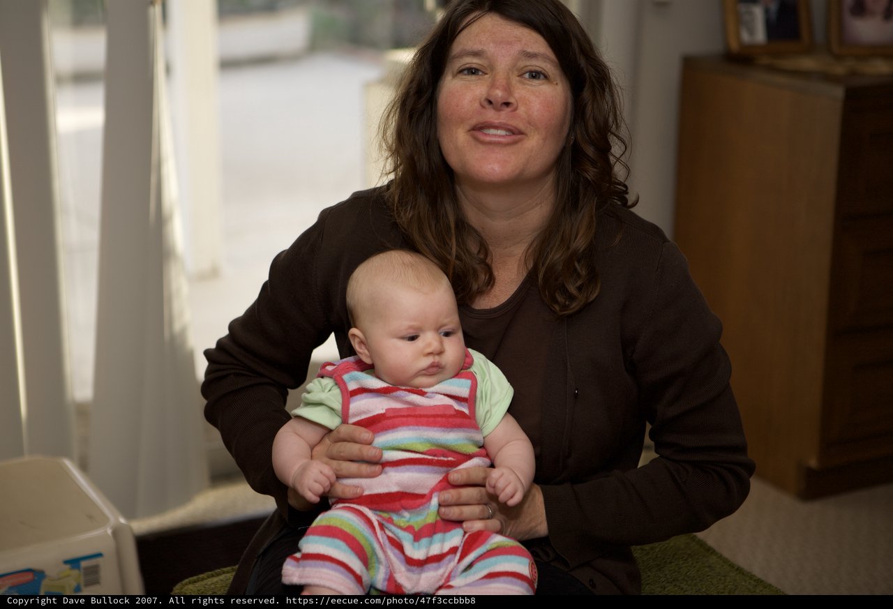 Mother Holding Infant in Colorful Striped Onesie