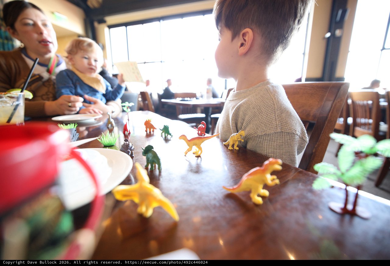 Family Dinosaur Play Time at Restaurant Table