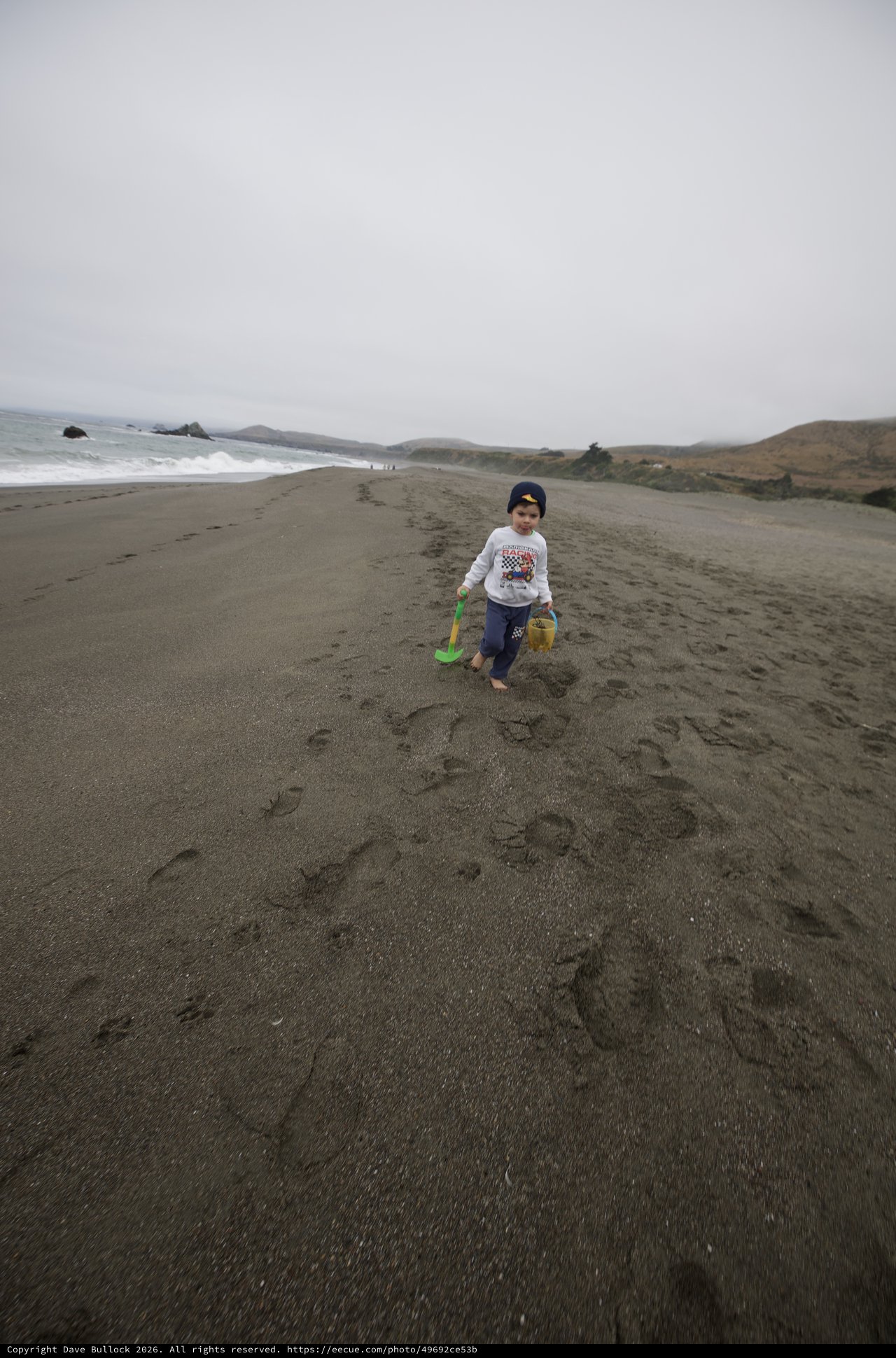 Young Explorer Walking Along a Gray Sandy Beach