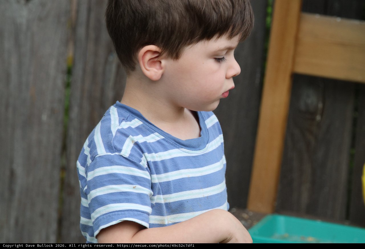 Young Boy in Striped Shirt Looking Down Thoughtfully