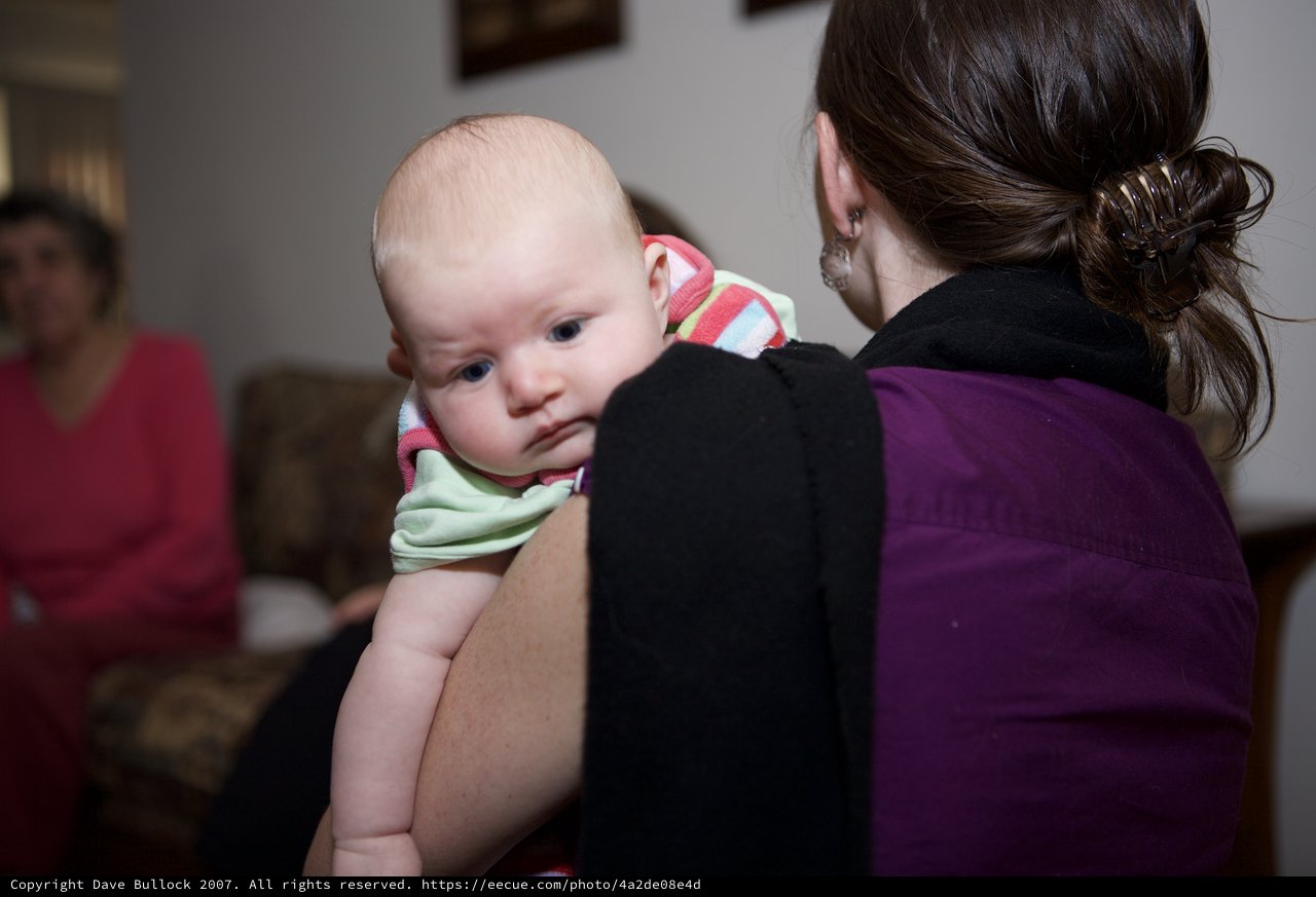 Baby Penelope Gazes Over Mother's Shoulder Indoors